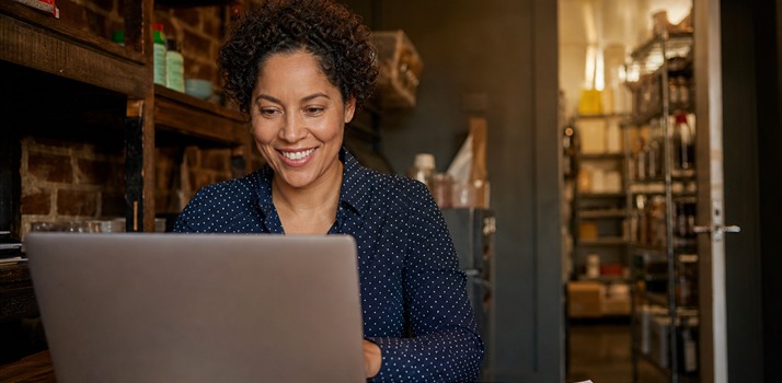 Small business owner smiling while working on a laptop to publish social content